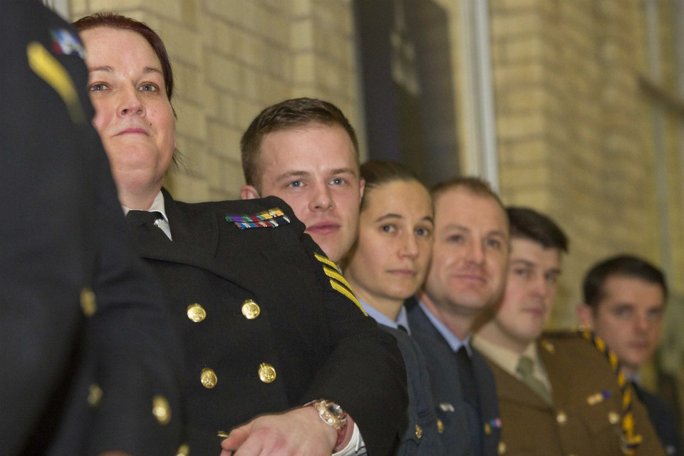 Armed Forces personnel in a line, listening to a speech