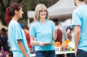 Senior woman directing volunteers at outdoor farmers' market