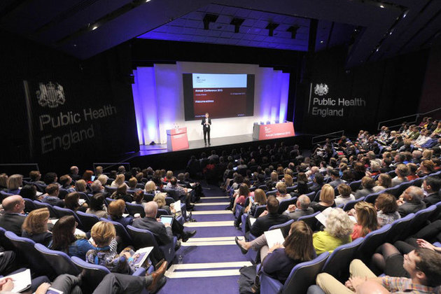 A man speaking on stage in front of an audience of people