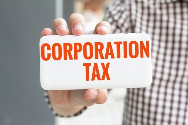 Hand holding a card saying corporation tax