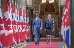 Canadian PM Justin Trudeau and UK PM Theresa May walking alongside Canadian and UK flags