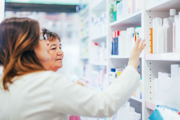 Pharmacist and customer search for medication on a pharmacy shelf