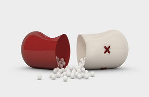 A red and white capsule split in half with small white balls coming out 
