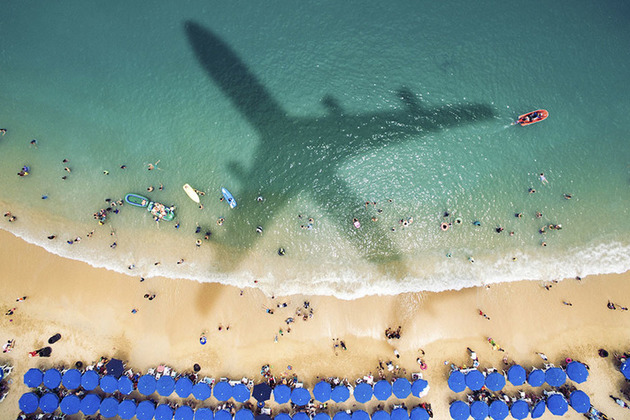 Image of a beach with the shadow of a plane flying overhead.