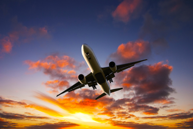 Boeing aeroplane takes off against sunset.