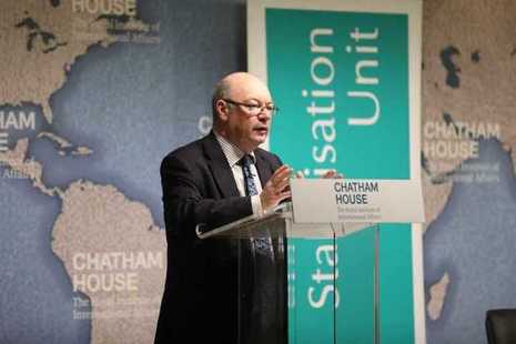 Minister for International Development Alastair Burt stands at a lectern with a map of the world behind him.