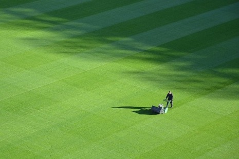 Groundsman mowing the grass of a sports field.