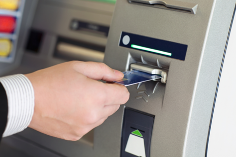 A man inserting his bank card into an ATM machine.