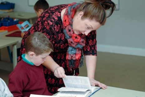 Primary school teacher helping pupil with his work