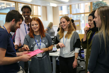 A group of young people stood working together in a classroom