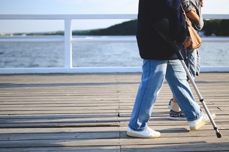 Woman using crutches while walking along pier