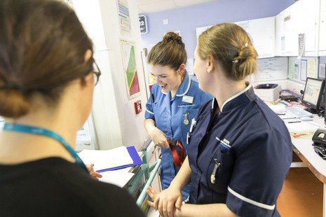 3 female nurses chatting and laughing.