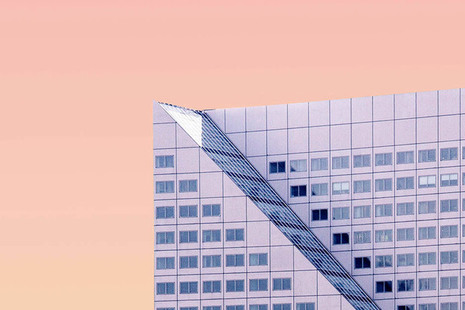 Sloped roof of a skyscraper set against a pink sky