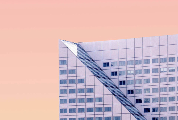 Sloped roof of a skyscraper set against a pink sky