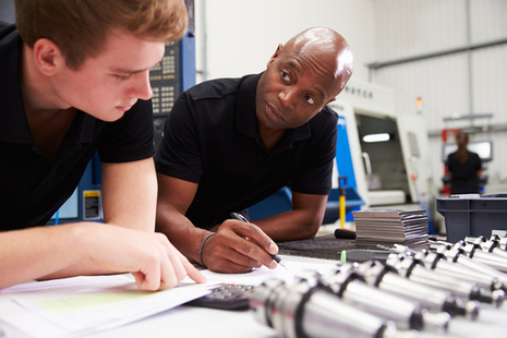 Stock image of an apprentice being helped with their work.