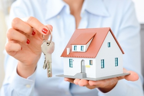 Hands holding keys and a miniature house.