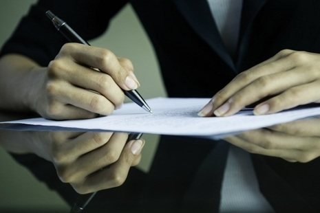 A picture of a woman writing on a document