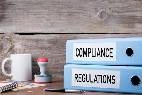 Two lever arch folders that say regulation and compliance