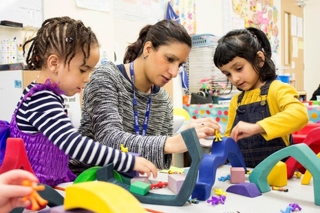 Childcare professional with 2 young girls playing at a crafts table