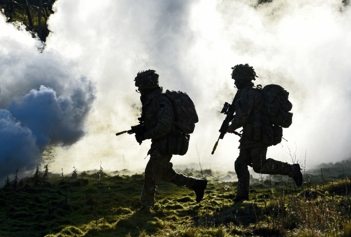 Two soldier silhouettes running through smoke