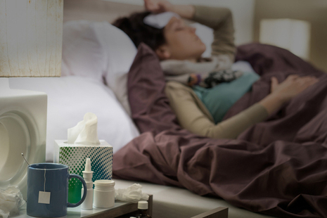 Female sick with flu in bed.