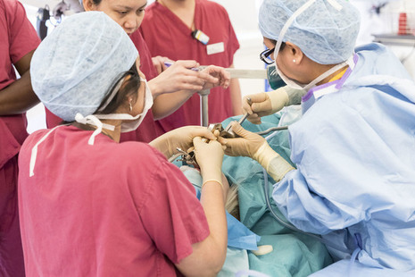 Staff in gowns and marks performing surgery in an operating theatre.