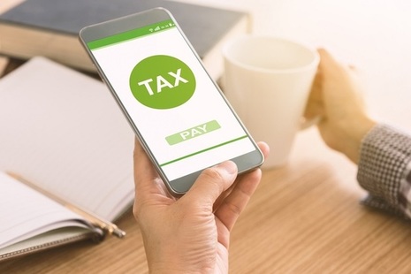 Image of hand holding a mobile phone with screen showing option to pay tax
