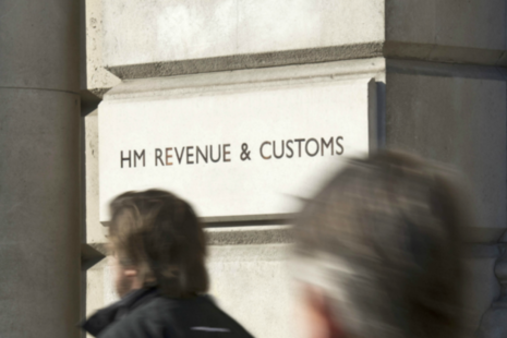 People walking past HM Revenue and Customs sign into 100 Parilament Street.