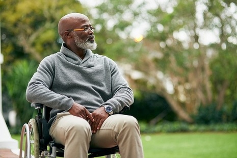 A man in a wheelchair sitting outside.