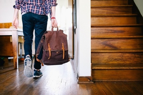 Teenager with school bag in hallway, seen from the back