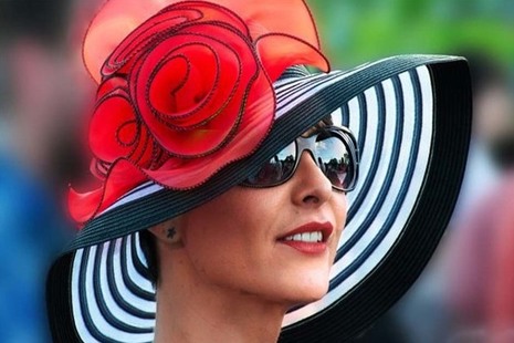 Woman wearing a large black and white striped hat with a red flower on it