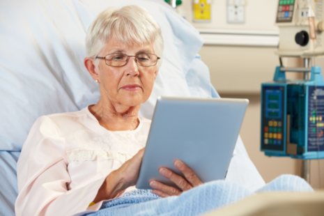 Older lady in bed using iPad in hospital