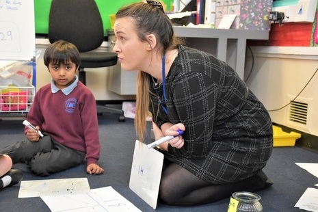 Male pupil sitting on carpet with teacher