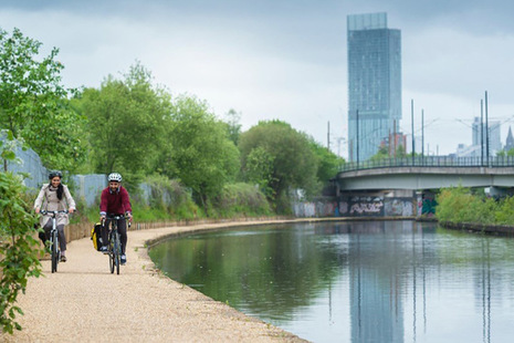 Picture of people cycling along a river.