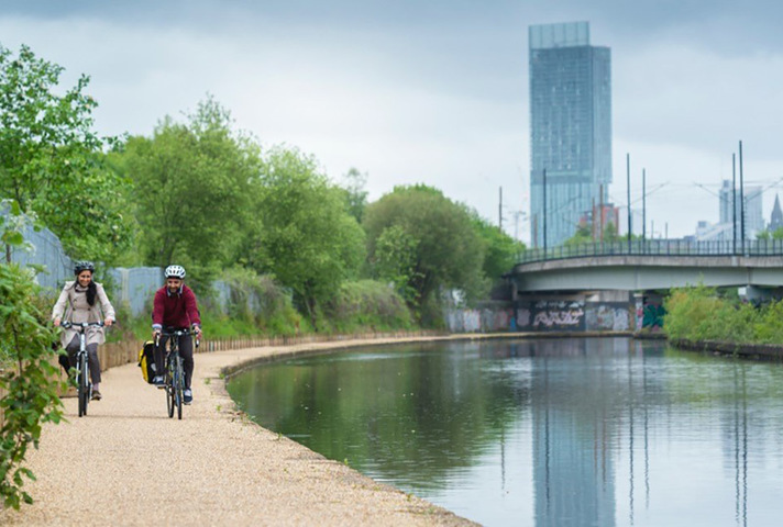 Picture of people cycling along a river.