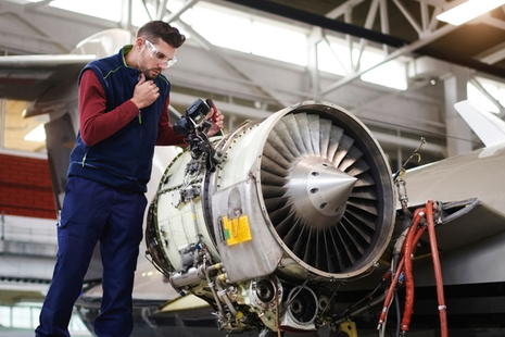 An engineer works on an aircraft turbine.