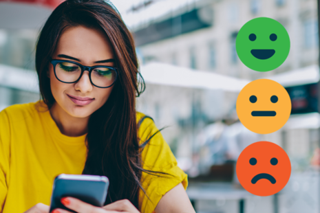A female looking at a smartphone with red, amber and green unhappy to smiling faces.