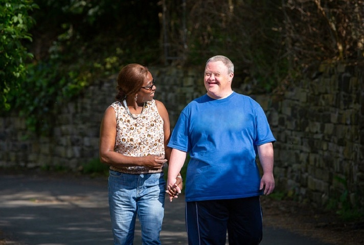 Carer and man with Down's syndrome walking down the street