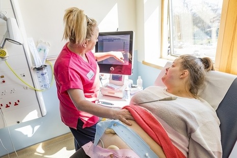 A pregnant woman having checks in a hospital consultation room.