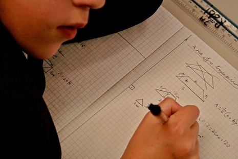 Close up of child writing in maths workbook