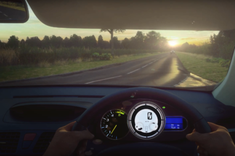 Computer generated imagery of the view from the driver's seat of a car, showing a road ahead, with a car travelling towards the driver