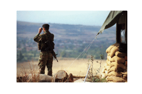 Army soldier looking out the fields with bonoculars