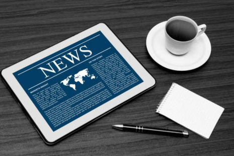 Tablet computer with the word "News" on it, next to a coffee mug.