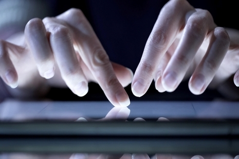 fingers using a touchpad lit up by a laptop screen