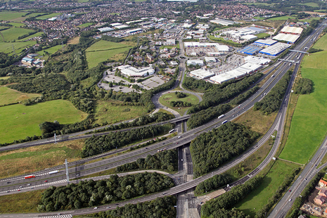 Aerial view of a section of motorway with junctions, a town and countryside