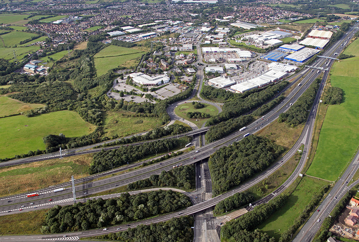 Aerial view of a section of motorway with junctions, a town and countryside