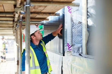 A construction worker analyses an incomplete wall.