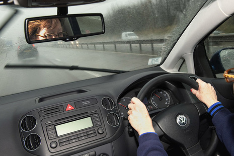 Photo of a driver, with their hands on a steering wheel