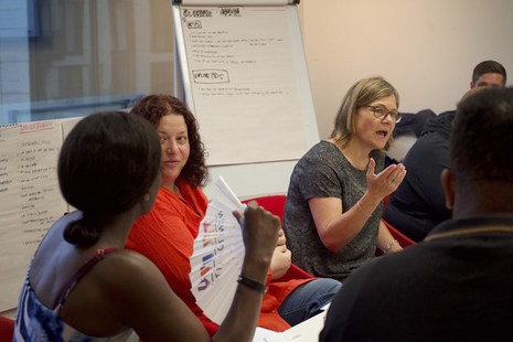a group of people discussing topics on a whiteboard