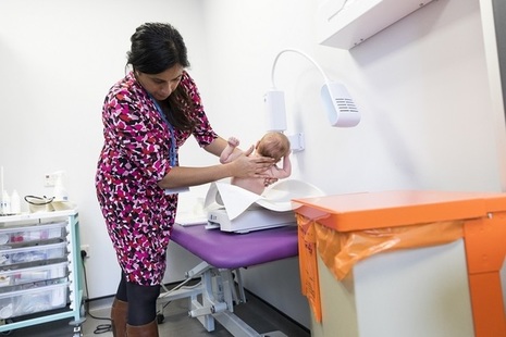 A doctor putting a baby onto weighing scales